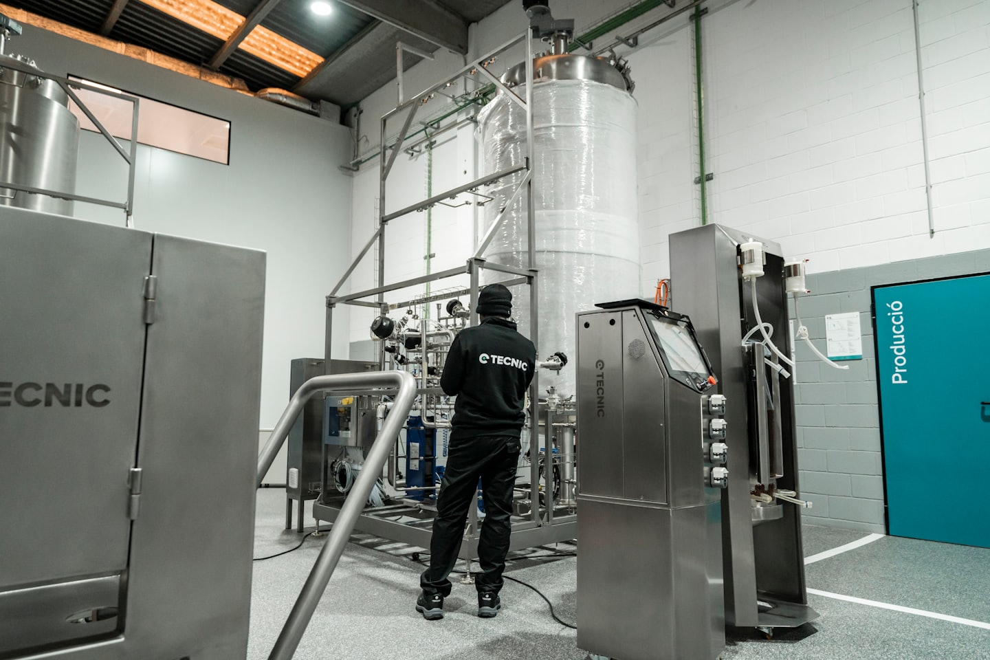 Tecnico che ispeziona complessi macchinari industriali in acciaio inossidabile.