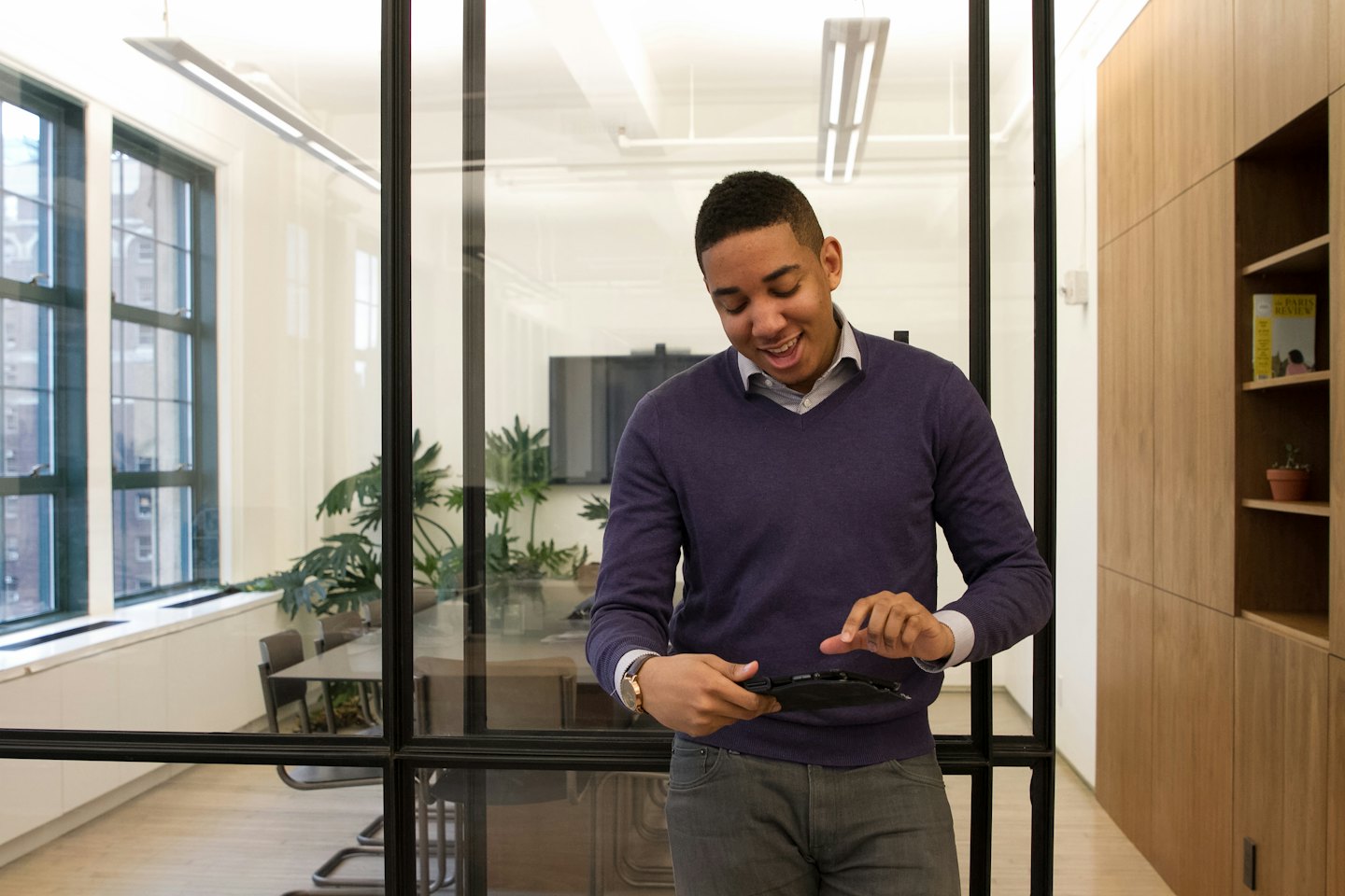 Un uomo sorride usando un tablet in un ufficio moderno.